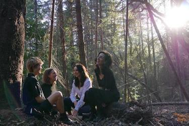 Four students relax and talk in the redwood forest.