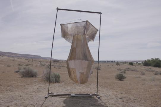 Hanging fabric sculpture that resembles an atomic bomb against a desert landscape
